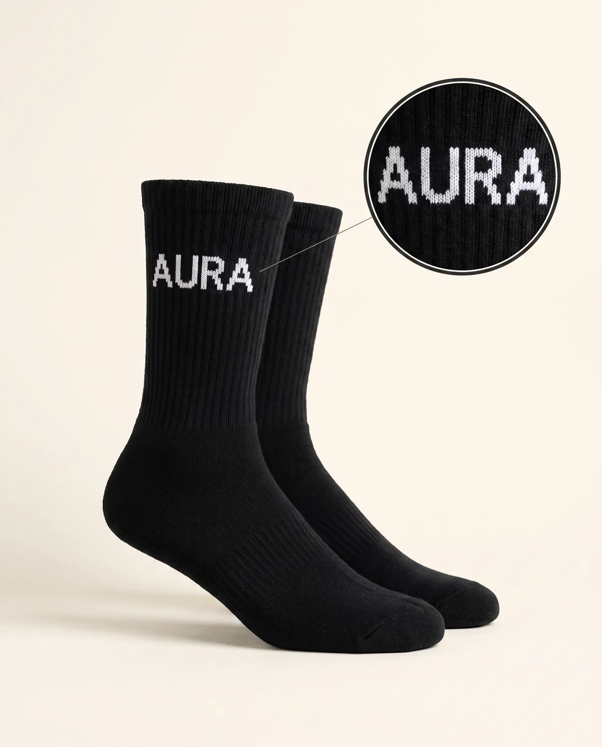 Black crew socks, white jacquard-knitted AURA sample mark on the cuff with zoom loupe